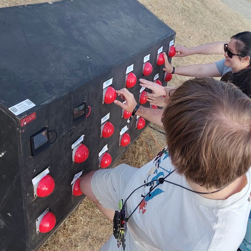 A team of people pressing buttons on a large interactive puzzle